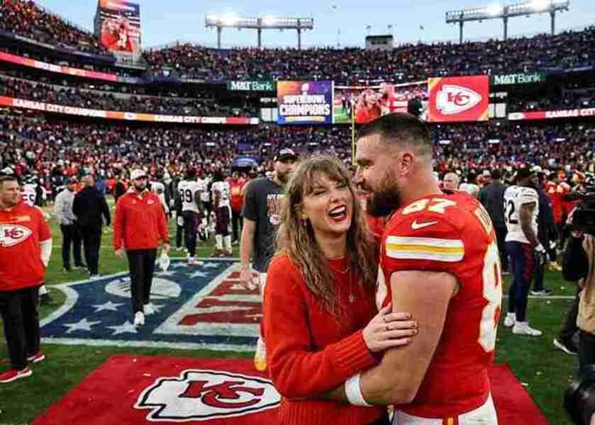 Taylor Swift hugging Travis Kelce on the field at a Kansas City Chiefs game